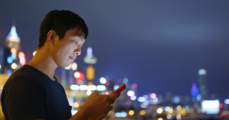 Man check on mobile phone in city at night
