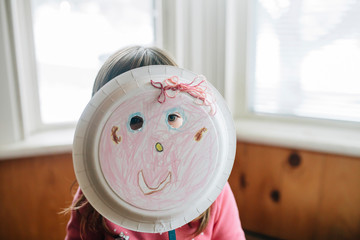 Girl holding plate mask at home