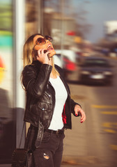 Obraz premium beautiful young girl smiling and talking on smart phone on street with blond hai, commercial model, and sunlight beautiful day