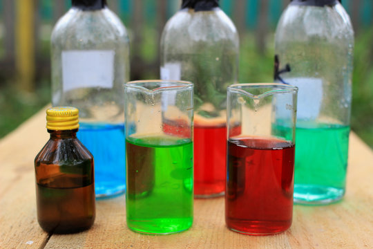 Colored chemical reagents in the beakers and bottles.