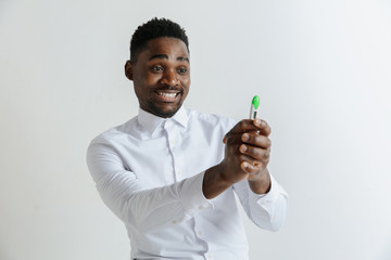 Young happy african american man looking at pregnancy test. Handsome smiling man inspired and delighted. Guy pleased because of result of pregnancy test.