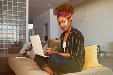 Cute american african female blogger working remotely on digital netbook with internet text....