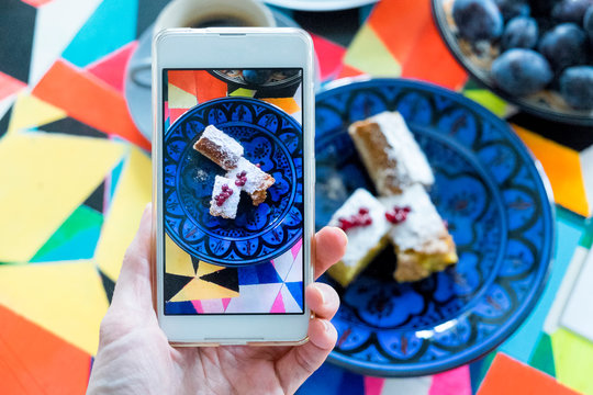 Cropped image of woman photographing sweet food served in plate