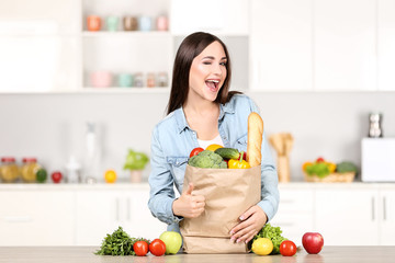 Beautiful woman standing on the kitchen with grocery shopping bag