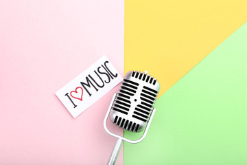Fototapeta na wymiar Vintage microphone and paper with text I Love Music on colorful background