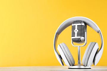 Vintage microphone with headphones on yellow background