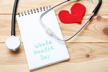 Text World Health Day with stethoscope and red heart on brown wooden table
