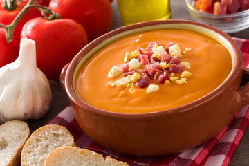 Typical Spanish salmorejo cream with ham and egg on wooden table