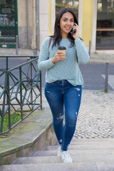 Fototapeta premium Happy woman talking on phone and walking up city stairs