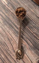 Powdered coffee in copper spoon on wooden background