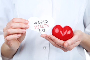 Paper with text World Health Day and red heart in female hands