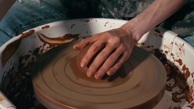 female ceramist making clay pot on potter wheel