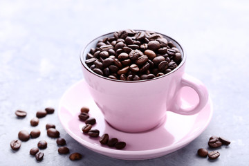 Coffee beans in pink cup on grey wooden table