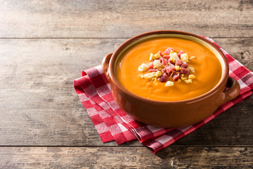 Typical Spanish salmorejo cream with ham and egg on wooden table. Copyspace
