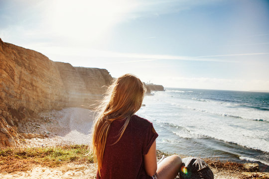 Rear View Of Woman Relaxing At Beach On Sunny Day