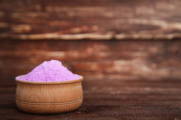 Holi powder in bowl on brown wooden table