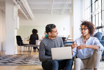 Business people talking while using laptop in office