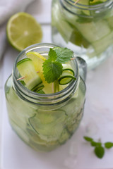 water with lime and cucumber, meat and ice in a glass mug.