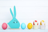 Colorful easter eggs with blue wooden rabbit on white background
