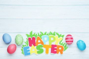 Colorful eggs with text Happy Easter on wooden table