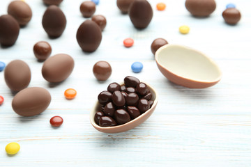 Chocolate easter eggs with colorful candies on wooden table