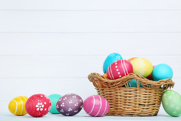Colorful easter eggs in basket on wooden background