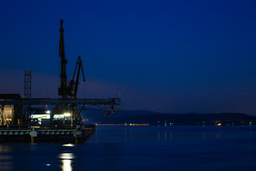 Port cranes over the water surface at night