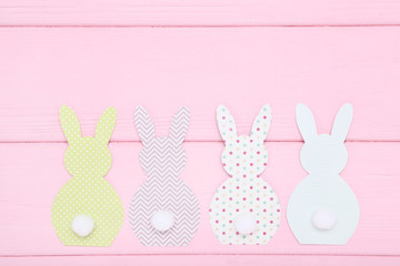 Easter paper rabbits on pink wooden table