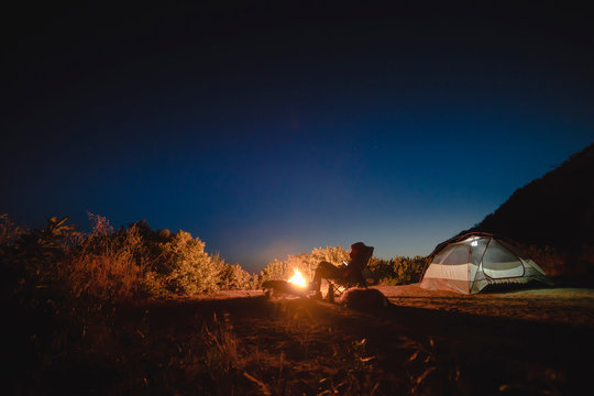 Woman using tablet computer while sitting at campsite against sky
