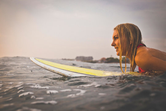 Side View Of Woman With Blond Hair Surfboarding In Sea