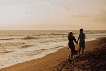 Naklejka premium beautiful happy laugh young hipster couple with golden retriever on beach. ocean an sand. waves. concepte of freedom and love.