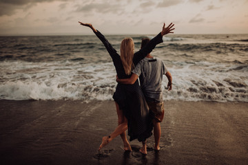 beautiful happy laugh young hipster couple with golden retriever on beach. ocean an sand. waves. concepte of freedom and love.
