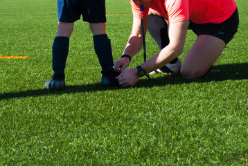 Fototapeta na wymiar Referee tying a shoe to a child soccer player
