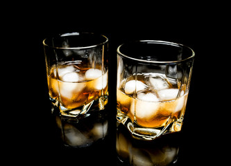 Whiskey with ice close up on a glass table isolated on a black background
