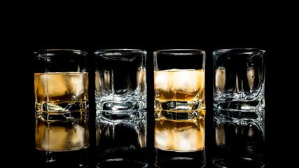 Whiskey with ice close up on a glass table isolated on a black background