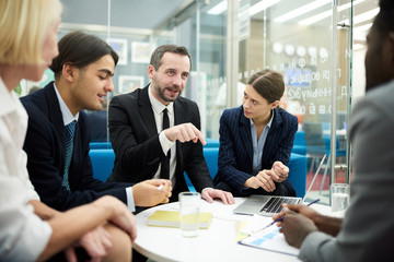 Portrait of mature businessman leading meeting with colleagues in office, copy space
