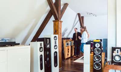 Couple buying new home stereo in Hi-Fi store - obrazy, fototapety, plakaty