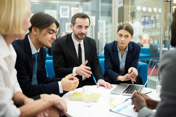 Portrait of mature businessman leading meeting with colleagues in office and gesturing actively, copy space