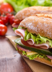 Long Baguette Sandwich with lettuce, slices of fresh tomatoes, ham, turkey breast and cheese