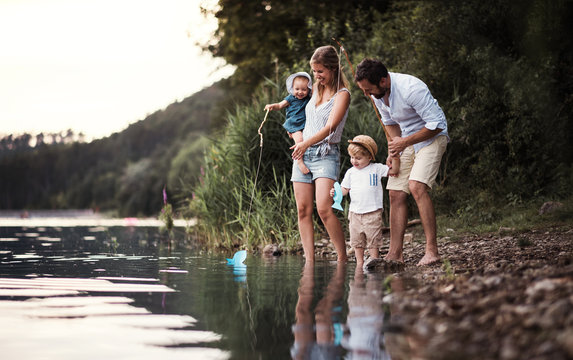A young family with two toddler children outdoors by the river in summer.