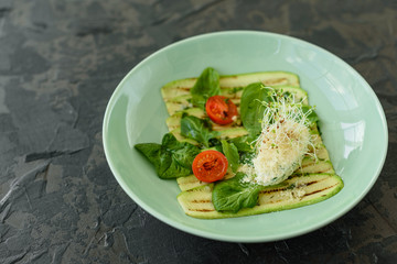 Salad from zucchini slices with cherry tomato, cream cheese and micro greens. Vegetarian food