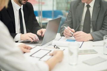 Crop shot of unrecognizable businessman holding pen discussing project with partners in meeting, copy space