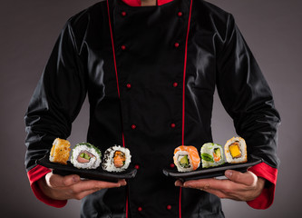 Fototapety  Szef kuchni trzymający talerze z kawałkami sushi.