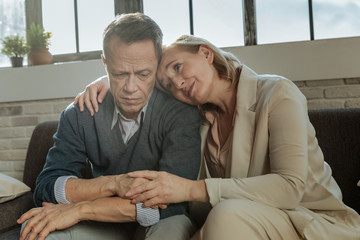 Sensitive good-looking woman crying on shoulder of her husband