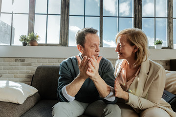 Good-looking middle-age couple looking at each other while sitting