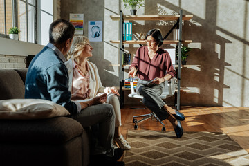 Attentive dark-haired therapist sitting with notebook on office chair