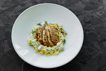 Dish with meat pieces, pasta, greens, sauce from a foie gras and the olive earth
