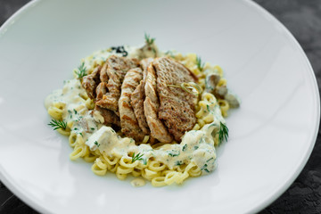 Dish with meat pieces, pasta, greens, sauce from a foie gras and the olive earth