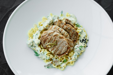 Dish with meat pieces, pasta, greens, sauce from a foie gras and the olive earth