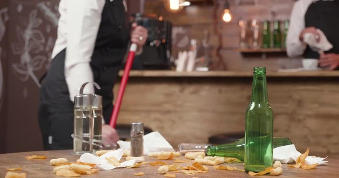 Restaurant staff cleaning the tables and floors after a busy day. Restaurant employees brooming ad throwing the trash.